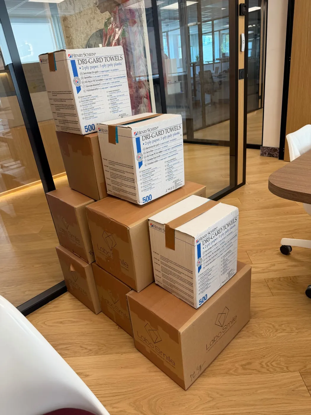 Cartons de consommables dentaires LaboSmile et Henry Schein empilés avant expédition